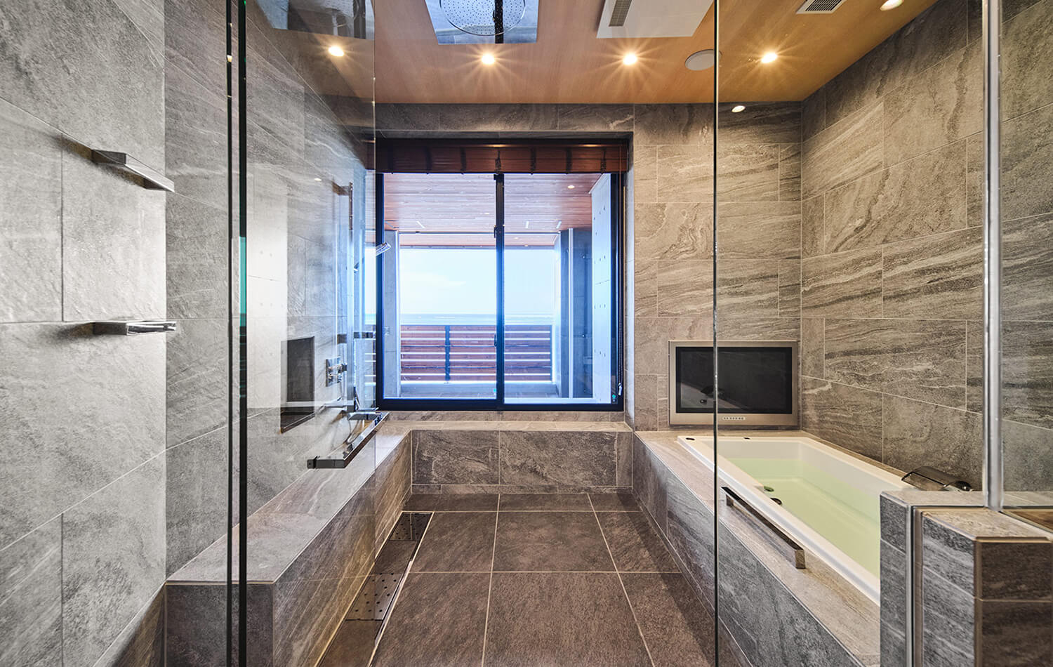 高級住宅のバスルーム。海を望む大開口により開放的な眺望を確保し、平田タイル「クオーツ」の石目調タイルを採用した自然素材調のデザイン。