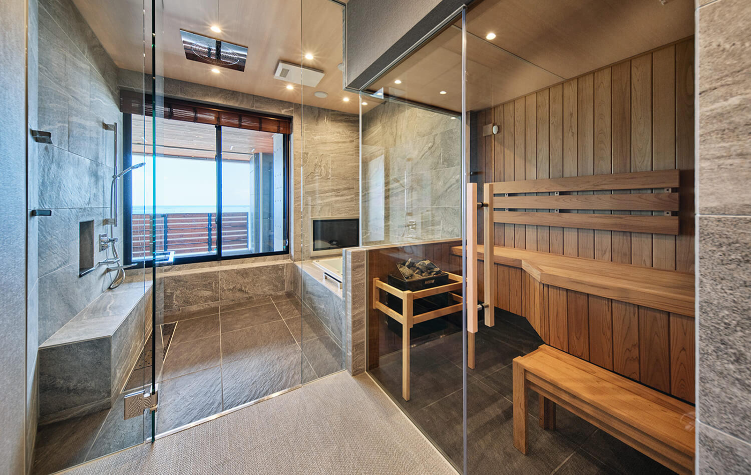高級住宅のバスルームとサウナ。アスペン材の白木を使用したサウナとガラスで繋げ、先に広がる海景を望む開放感を演出した。